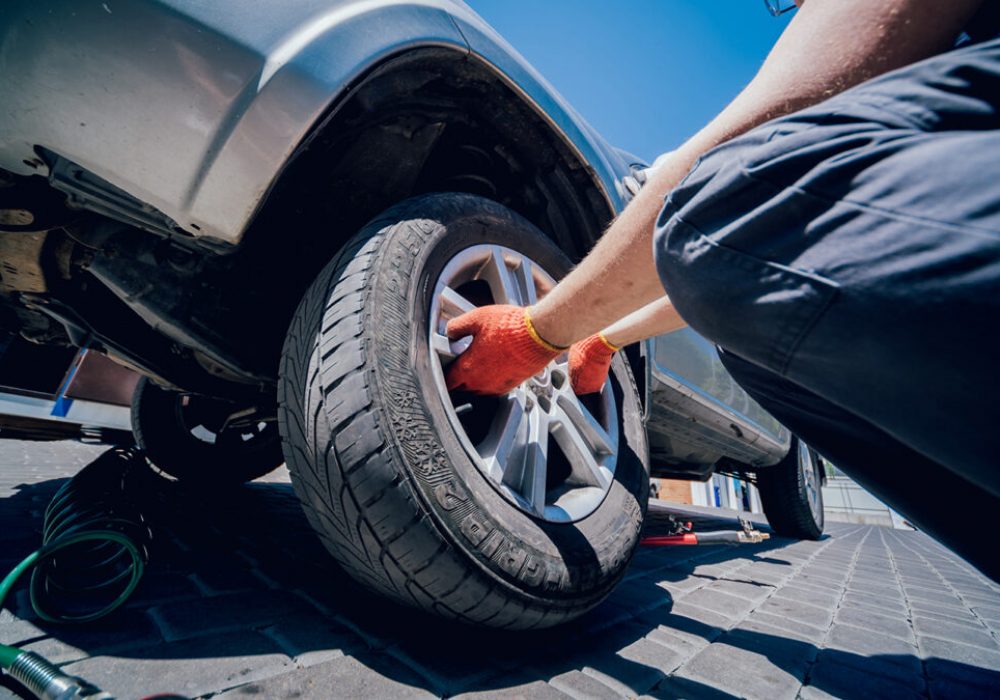 Professional car mechanic replace tire on wheel. Auto repair service.
